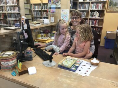 Librarian with children at the library checking out books.